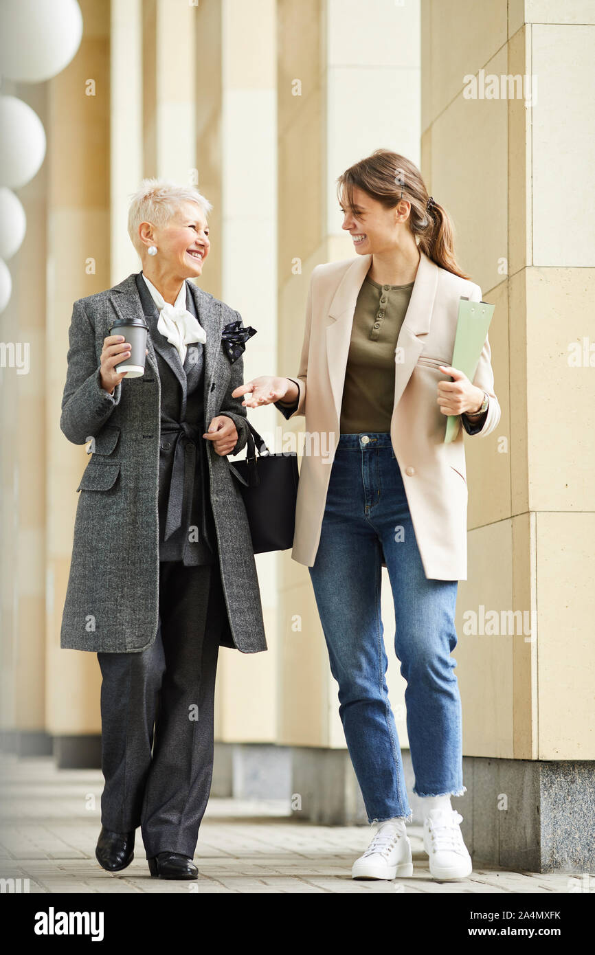 Deux professionnels des femmes dans des vêtements élégants parler et rire en se promenant dans la rue en plein air Banque D'Images