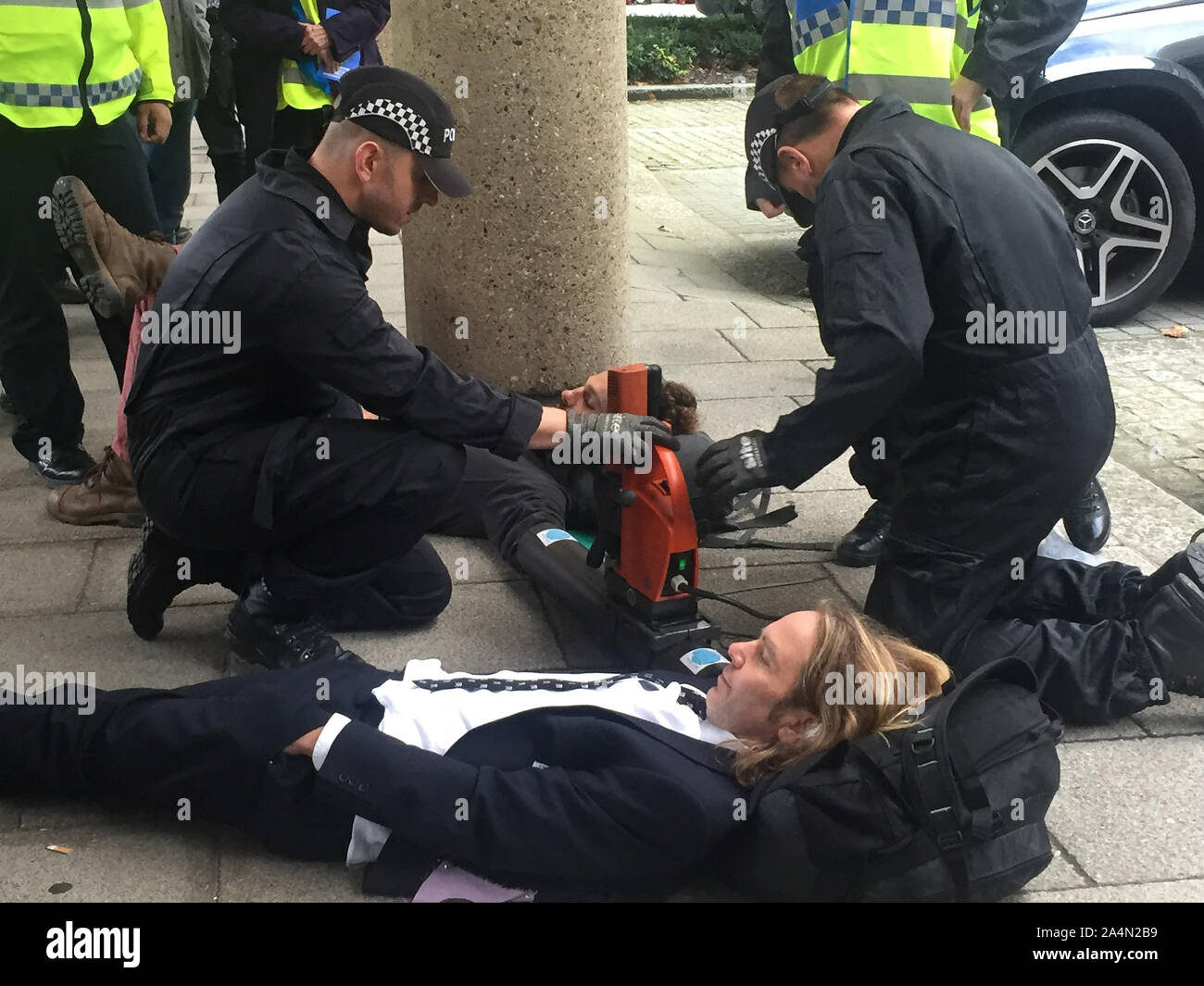 La police utilise un foret magnétique pour essayer de libérer le bras de deux manifestants rébellion Extinction verrouillé dans un tube de métal sous Millbank Tower à Londres. Banque D'Images