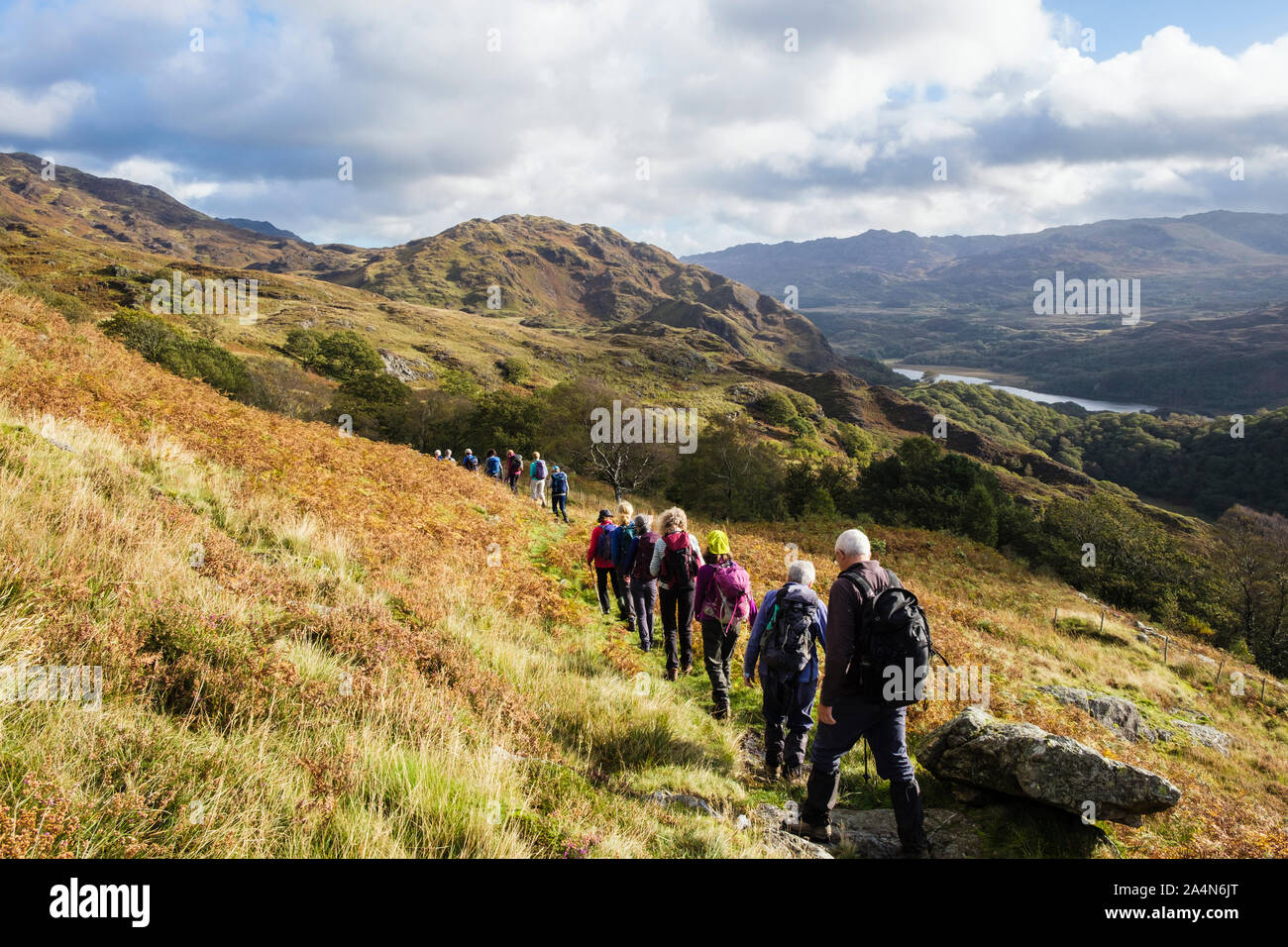 Groupe de Randonneurs marchant dans une longue ligne sur le chemin d'un pays au-dessus de Nant Gwynant dans collines du Parc National de Snowdonia. , Beddgelert Gwynedd, au nord du Pays de Galles, Royaume-Uni Banque D'Images