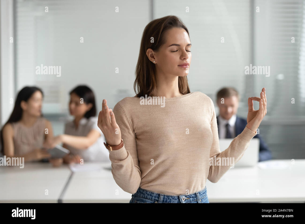 Conscient young businesswoman meditating, faisant de l'exercice de yoga in office Banque D'Images