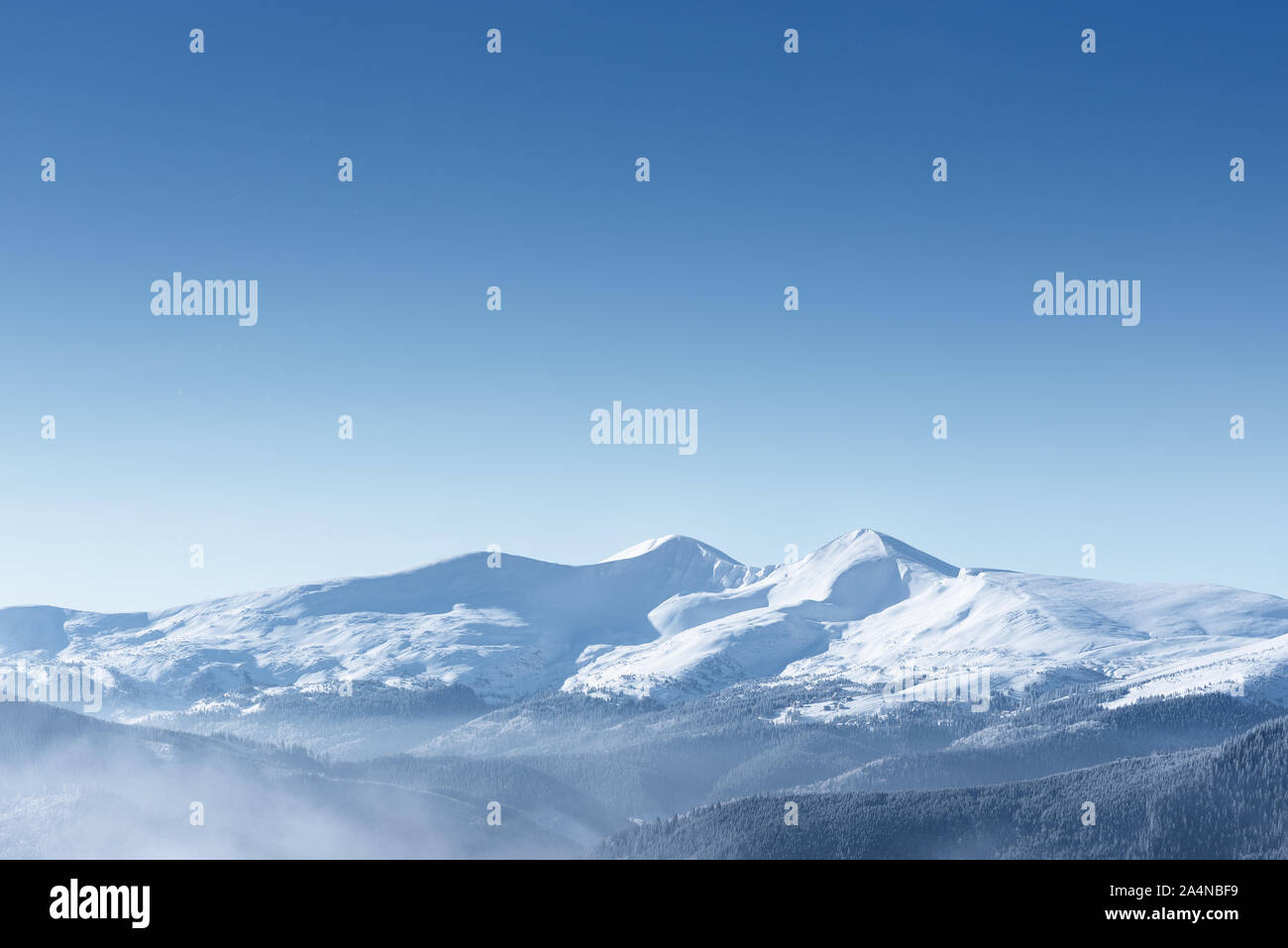 Fond d'hiver avec copie espace pour le texte. Sommets de montagnes couvertes de neige et ciel bleu clair Banque D'Images