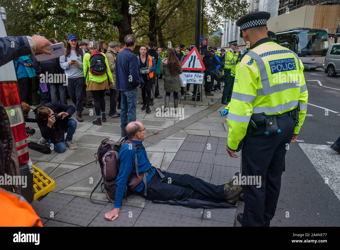 Londres, Royaume-Uni. 15 octobre 2019. L'homme qui était assis sur la route est remis en question et arrêté par la police.Bien que la police a interdit toute rencontre XR manifestations à grand Londres en vertu de l'article 14 de la Loi sur l'ordre public de 1986, les gens sont venus protester devant le MI5 o9n Millbank sur avenir prédit une pénurie de nourriture. La police a fouillé des militants et a fait une arrestation lorsqu'un homme s'est assis sur la route. Les activistes étaient toujours en train d'arriver car j'ai dû partir. Peter Marshall/Alamy Live News Banque D'Images