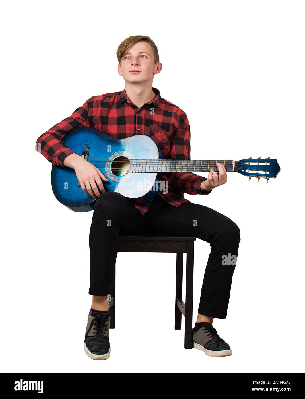 Portrait de l'adolescent garçon talentueux à jouer sur la guitare acoustique assis sur une chaise isolée sur fond blanc. Beaucoup de leçons de musique fo Banque D'Images