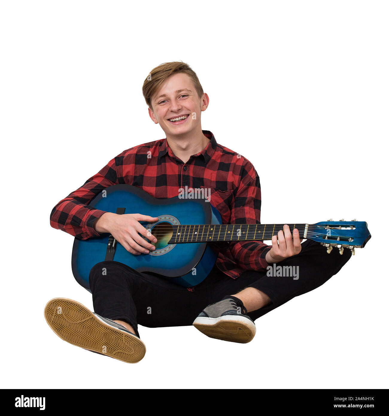 Portrait de l'adolescent garçon talentueux à jouer sur la guitare acoustique assis sur le plancher isolé sur fond blanc. Beaucoup de leçons de musique f Banque D'Images