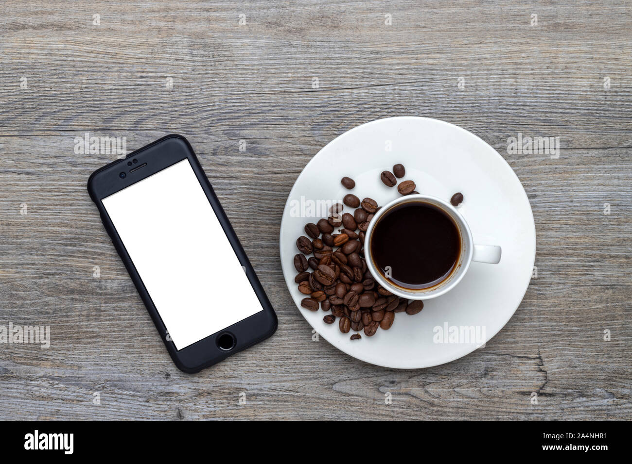 Tasse de café avec des haricots sur une table en bois avec un smartphone avec écran blanc pour le message Banque D'Images