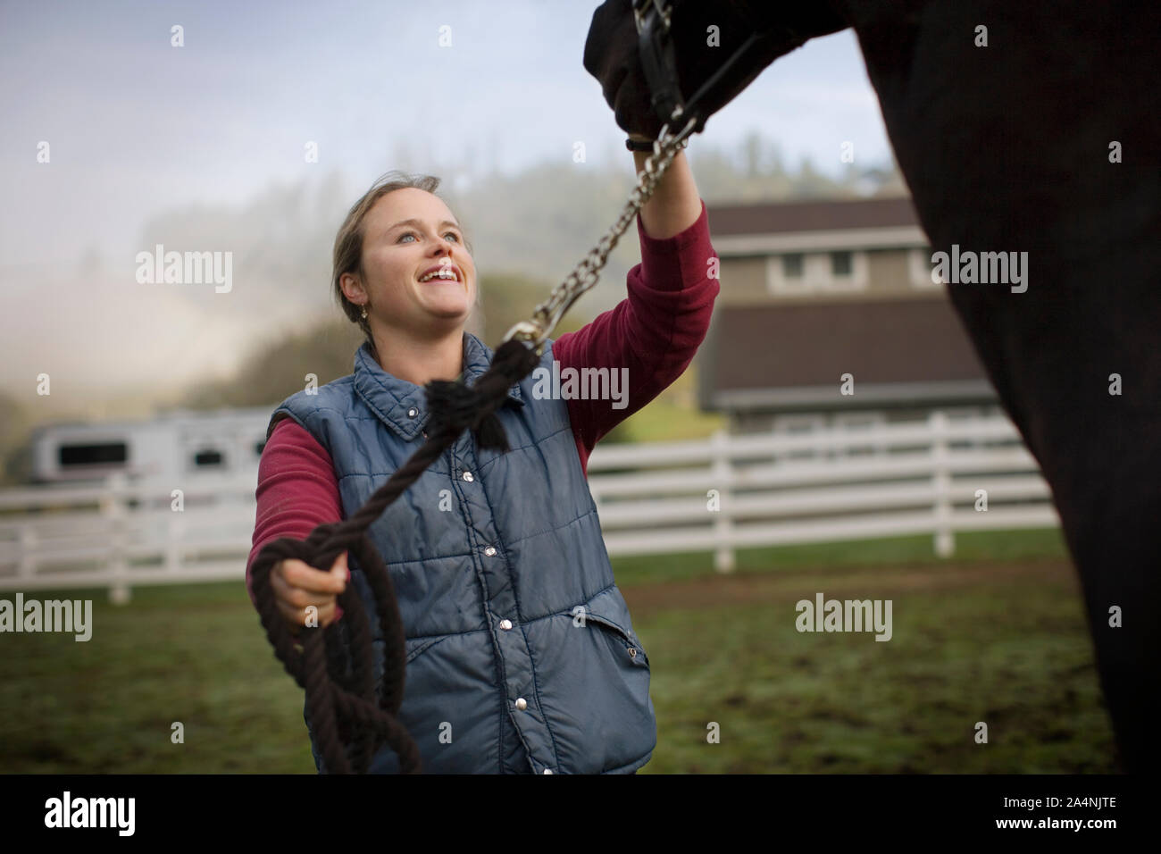 Jeune femme debout dans un enclos avec son cheval. Banque D'Images