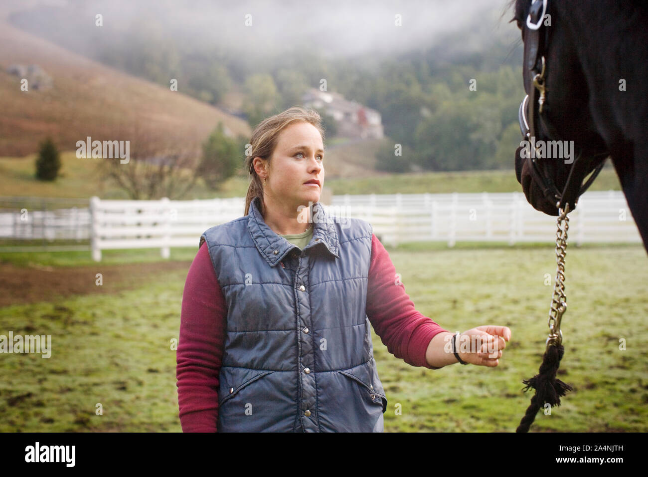 Jeune femme debout dans un enclos avec son cheval. Banque D'Images