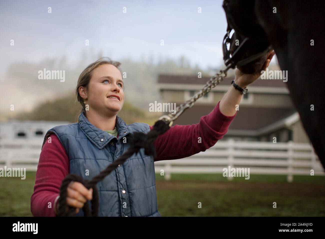 Jeune femme debout dans un enclos avec son cheval. Banque D'Images