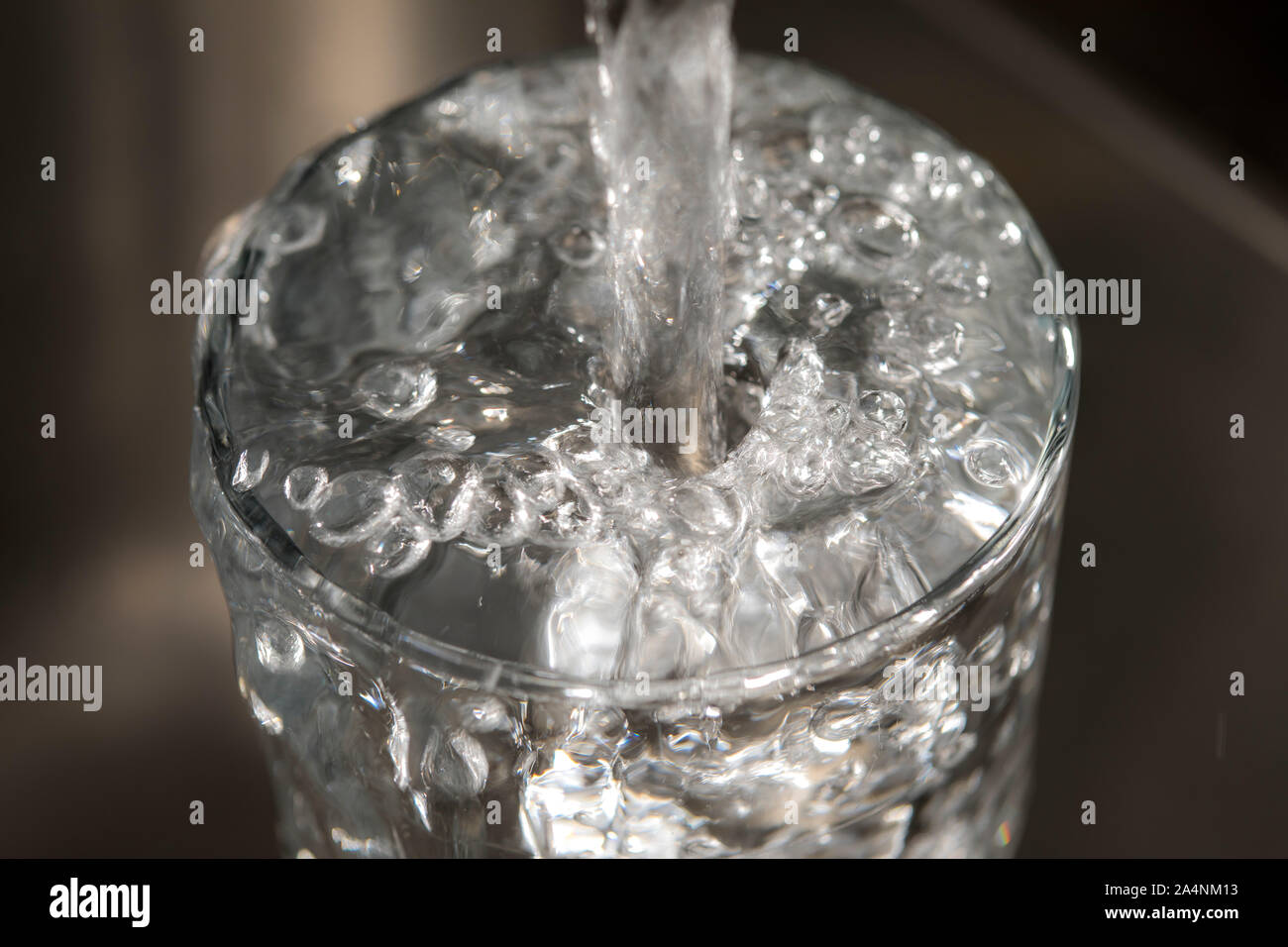 L'eau coule d'un robinet dans un verre. Symbole : la consommation d'eau, gaspillage d'eau. Banque D'Images