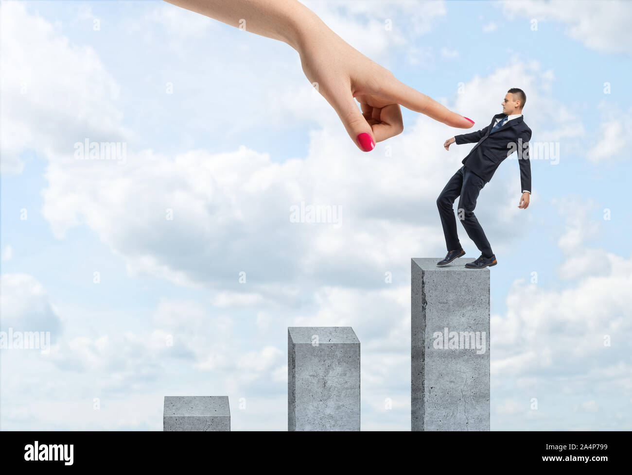 Businessman en équilibre sur la colonne de béton verticaux avec une main de femme géant pointant sur lui. Banque D'Images