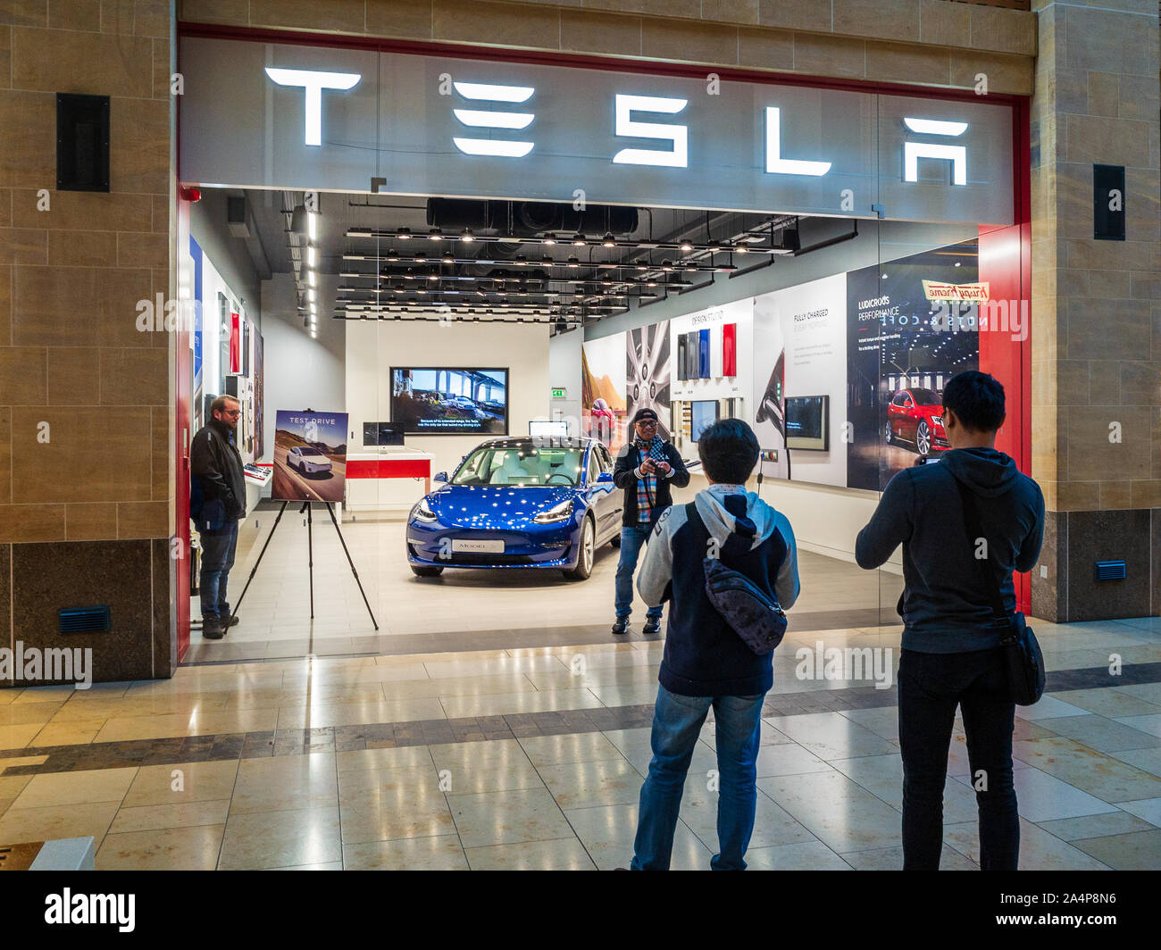 Tesla Showroom - les touristes prennent des photos devant la voiture Tesla Model 3 dans une concession Tesla à Cambridge Banque D'Images