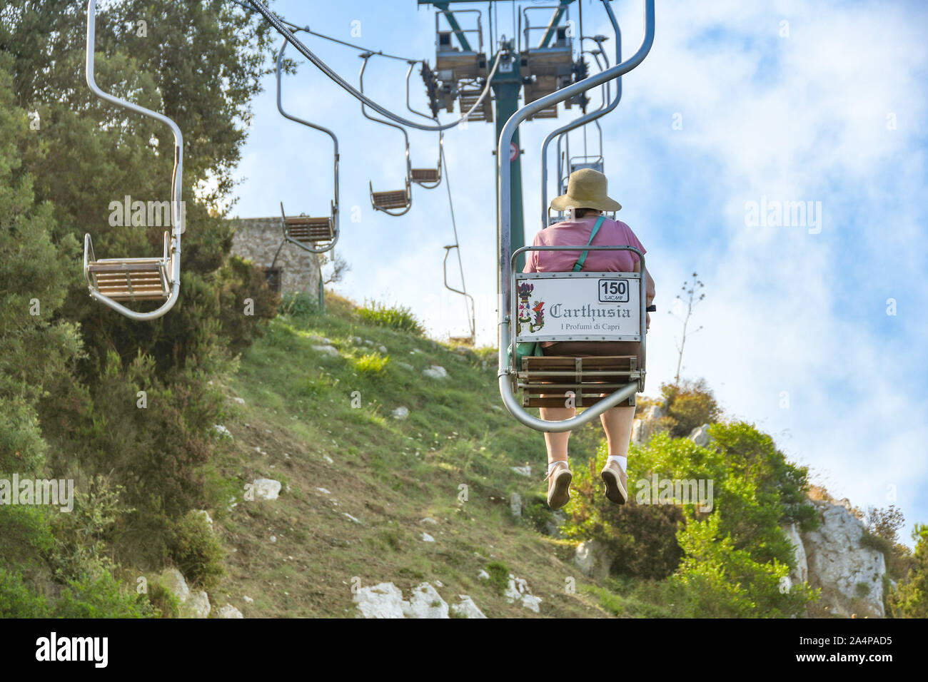 ANACAPRI, à l'île de Capri, ITALIE - AOÛT 2019 : personne sur un télésiège monte ou descend le long de la montagne jusqu'au sommet du Mont Solaro, Anacapri ci-dessus Banque D'Images
