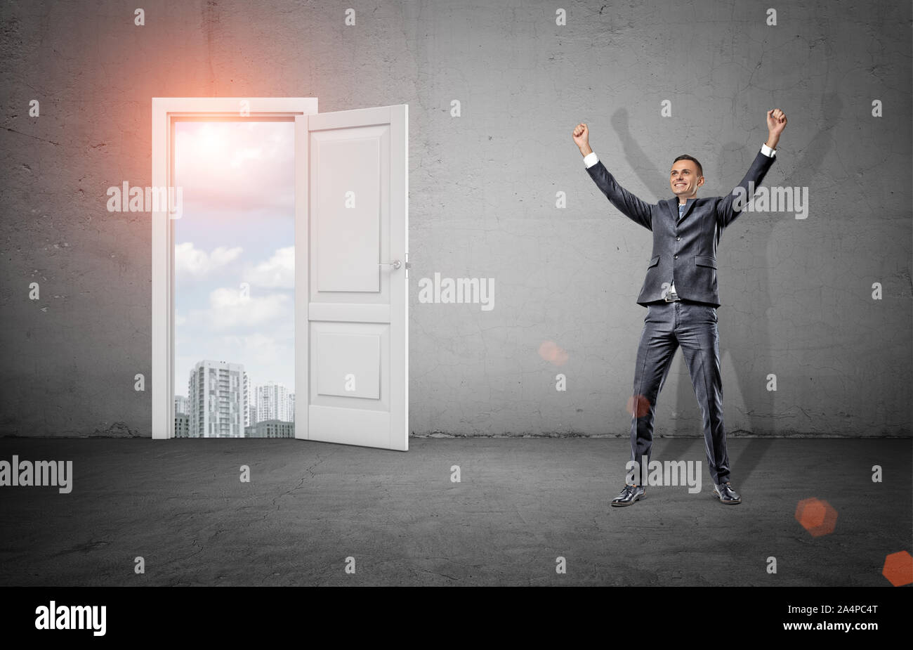 Victorieux d'un businessman with arms raised up se dresse sur un fond de béton près d'une porte où des bâtiments de la ville. Banque D'Images