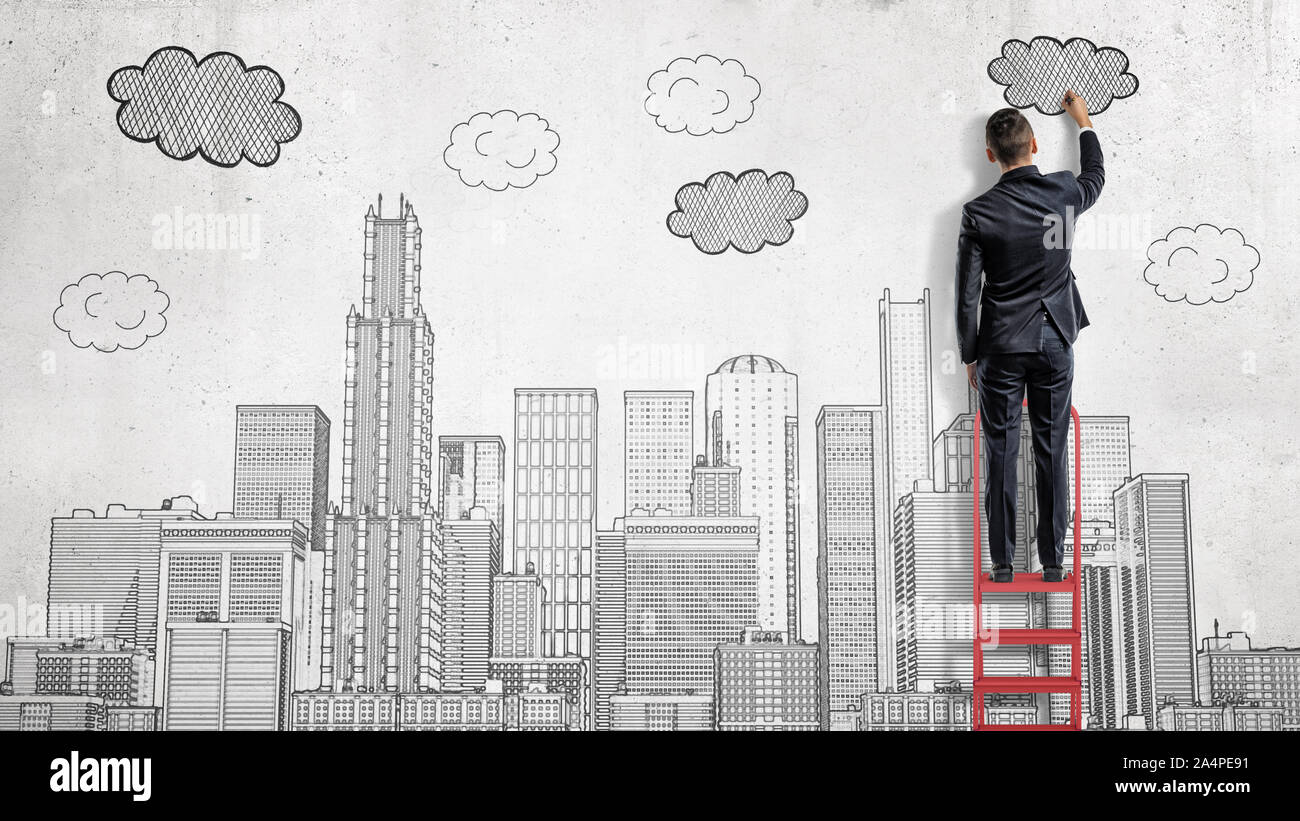 Un homme se tient sur une échelle et tire une grande ville avec des nuages au-dessus des gratte-ciel. Banque D'Images