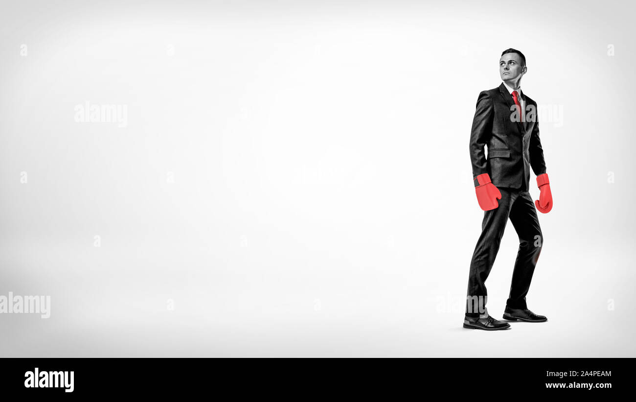 Un homme d'affaires est en demi-tour sur un arrière-plan tout en portant un costume rouge et des gants de boxe. Banque D'Images