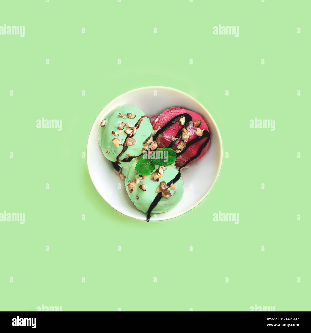 La pistache et glace à la fraise de caramel, de noix et de menthe sur bol blanc sur fond bleu vert menthe. Beau dessert. Coup de frais généraux. Mise à plat, vue du dessus. Close up, copiez l'espace. Banque D'Images