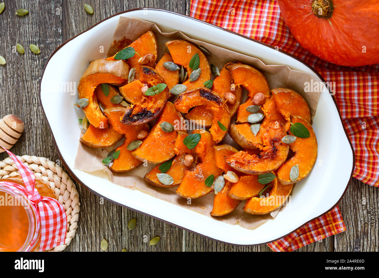 Tranches de potiron cuit au four avec du miel, les noix, la cannelle, les  graines, la menthe. Morceaux de potiron couché sur le papier cuisson dans  un bol. L'alimentation saine, dessert Photo