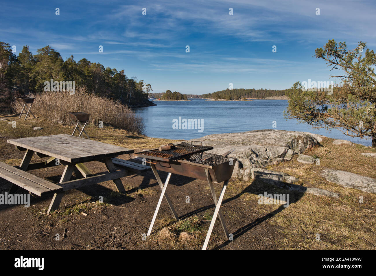 Barbecue à la rouille et table de pique-nique extérieure en bois par lac, réserve naturelle de Bjorno (Bjorno Naturareservat), archipel de Stockholm, Suède Banque D'Images