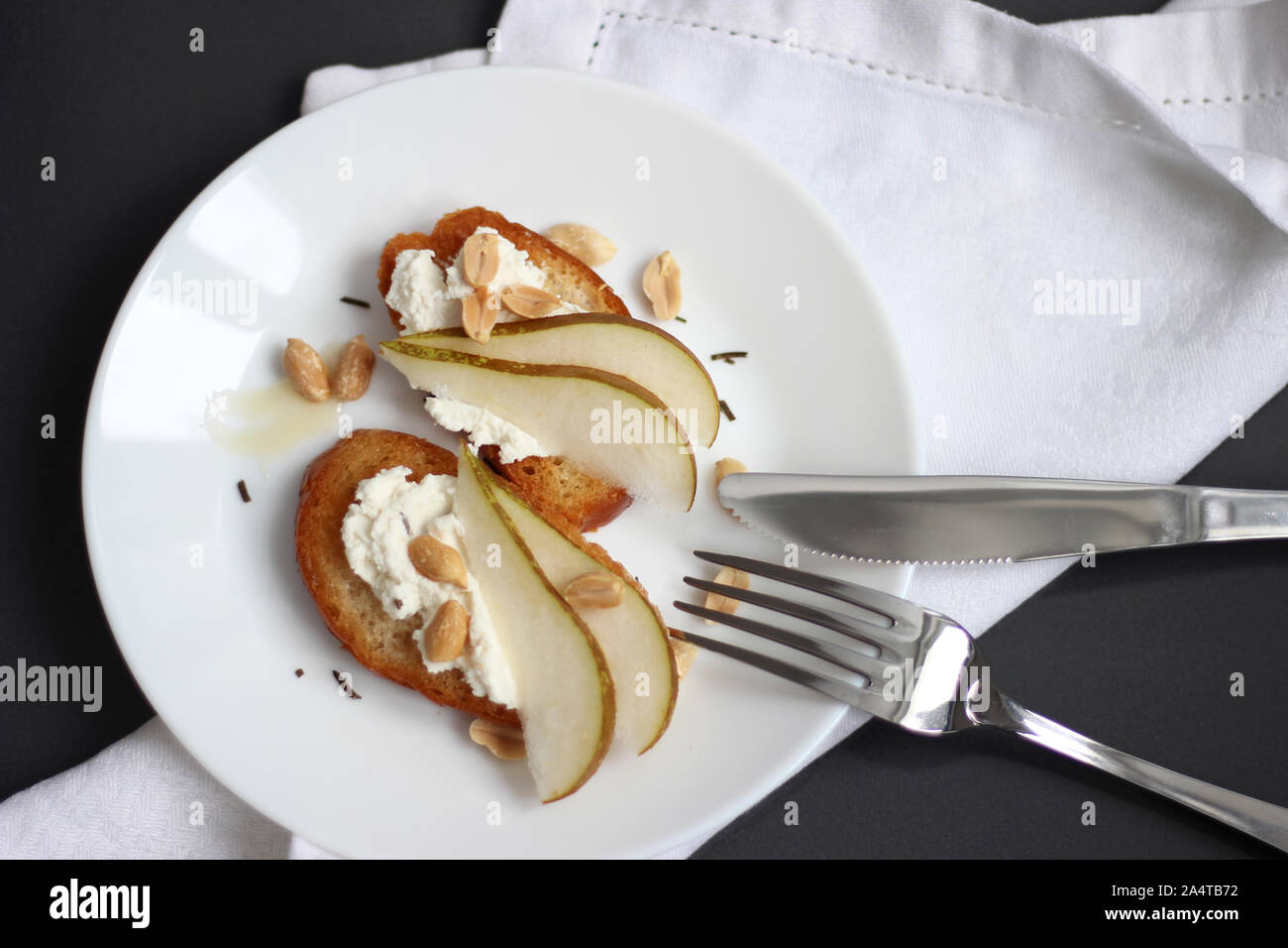 Crostini avec ricotta de tranches de poire et les arachides sur un fond sombre. Le petit-déjeuner, le déjeuner Table. Banque D'Images