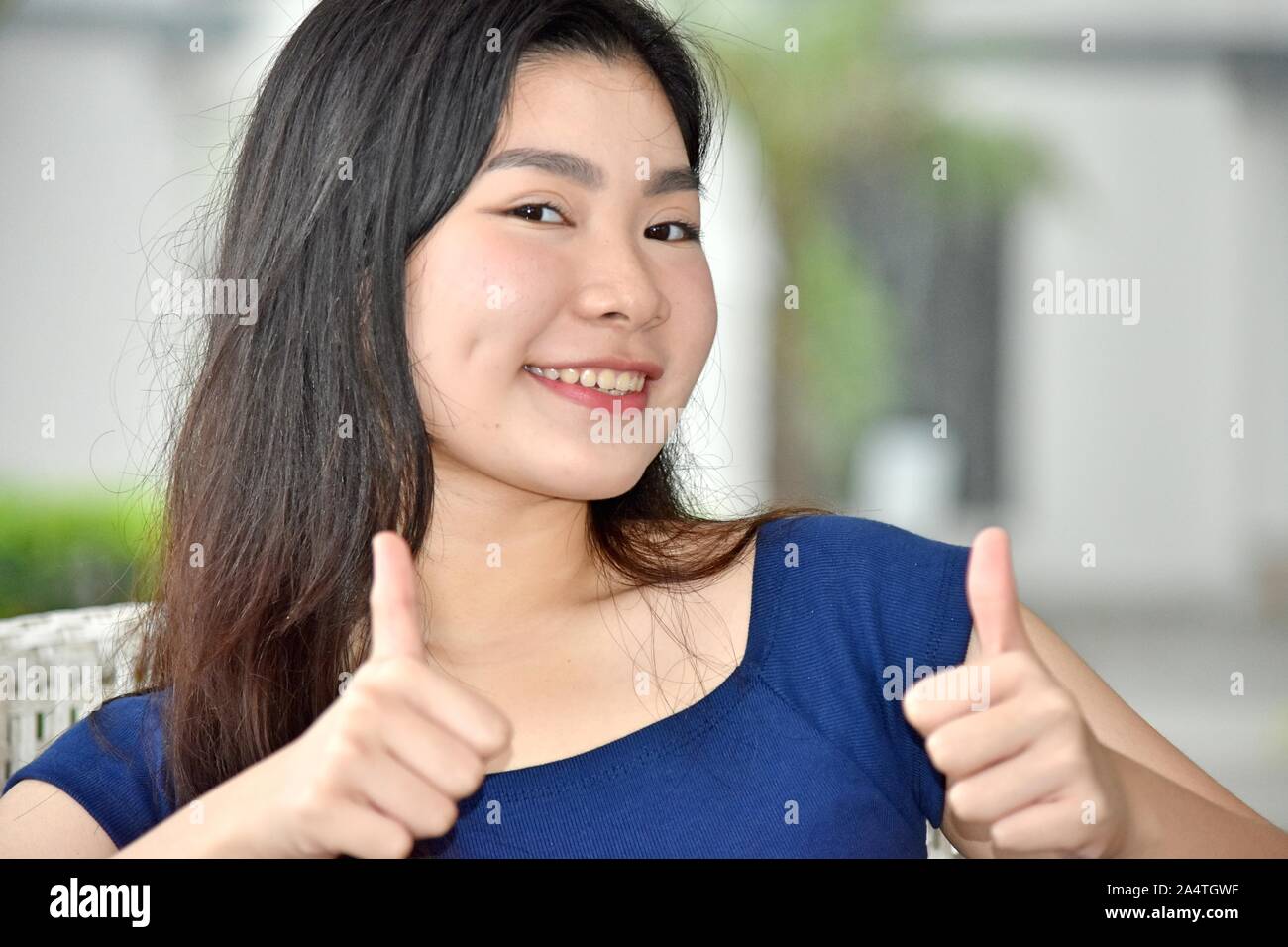 Fille de l'école chinoise avec Thumbs Up With Books Banque D'Images