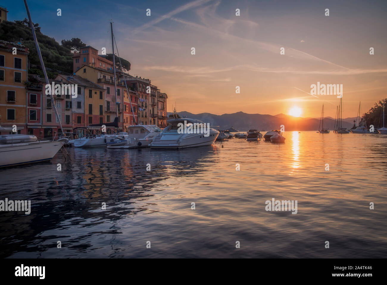 Bateaux amarrés dans la baie et beau lever de soleil à Portofino, Italie, vu de l'angle faible niveau d'eau avec le soleil se reflétant dans l'eau calme Banque D'Images