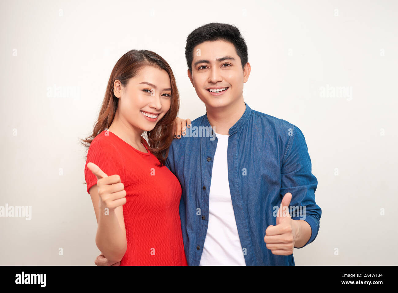 Jeune couple sur fond isolé avec sourire heureux face à la recherche et en pointant sur le côté avec thumb up Banque D'Images