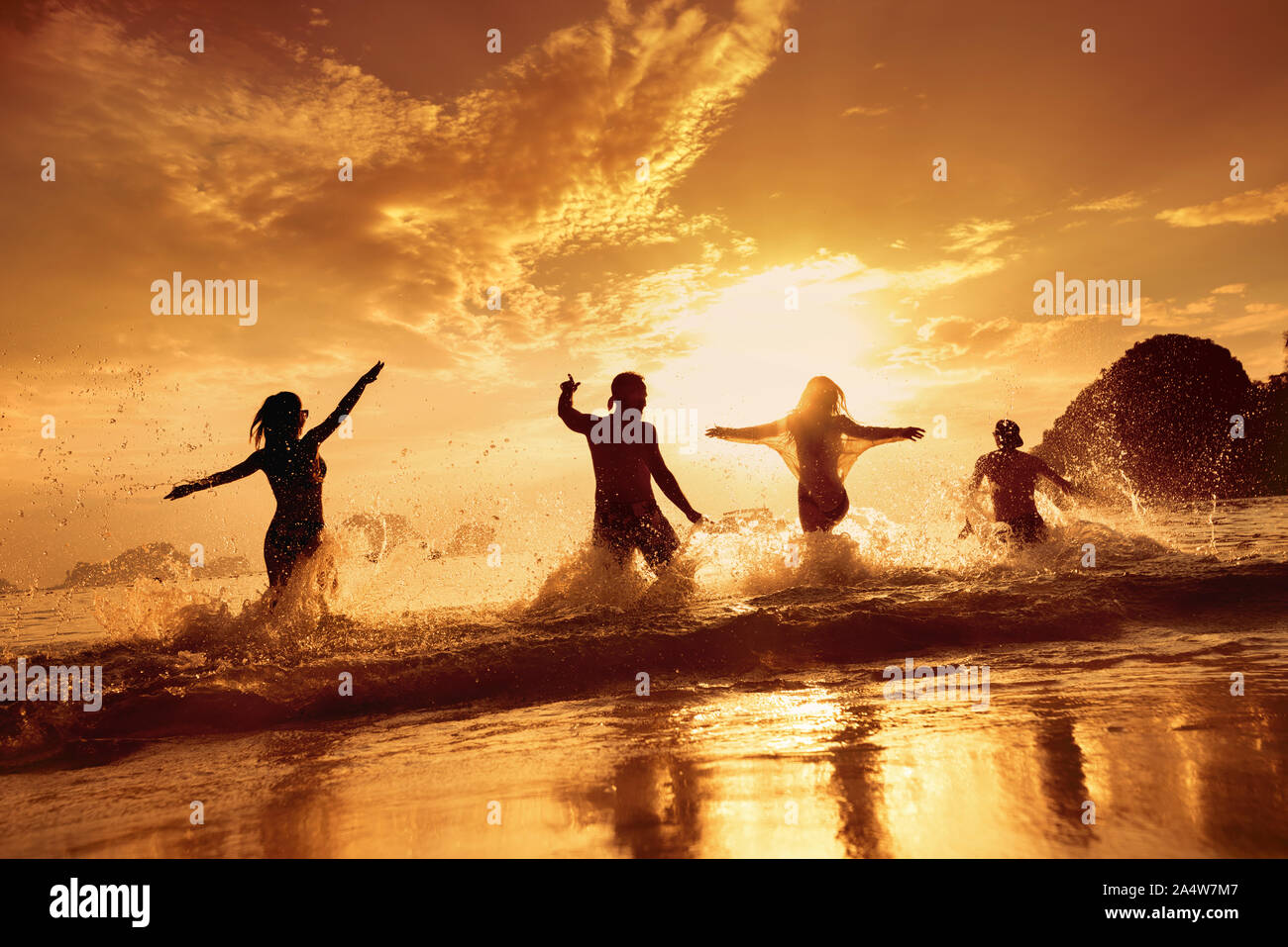 Quatre amis heureux s'exécute et s'amusant à beau coucher de soleil mer plage Banque D'Images