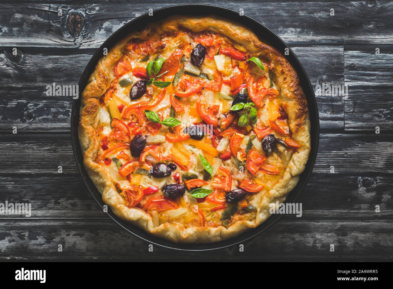 Des pizzas aux légumes sur un fond sombre. La pizza est vue de dessus et de l'est dans un rond de cuisson, copie de l'espace sur les côtés. Banque D'Images