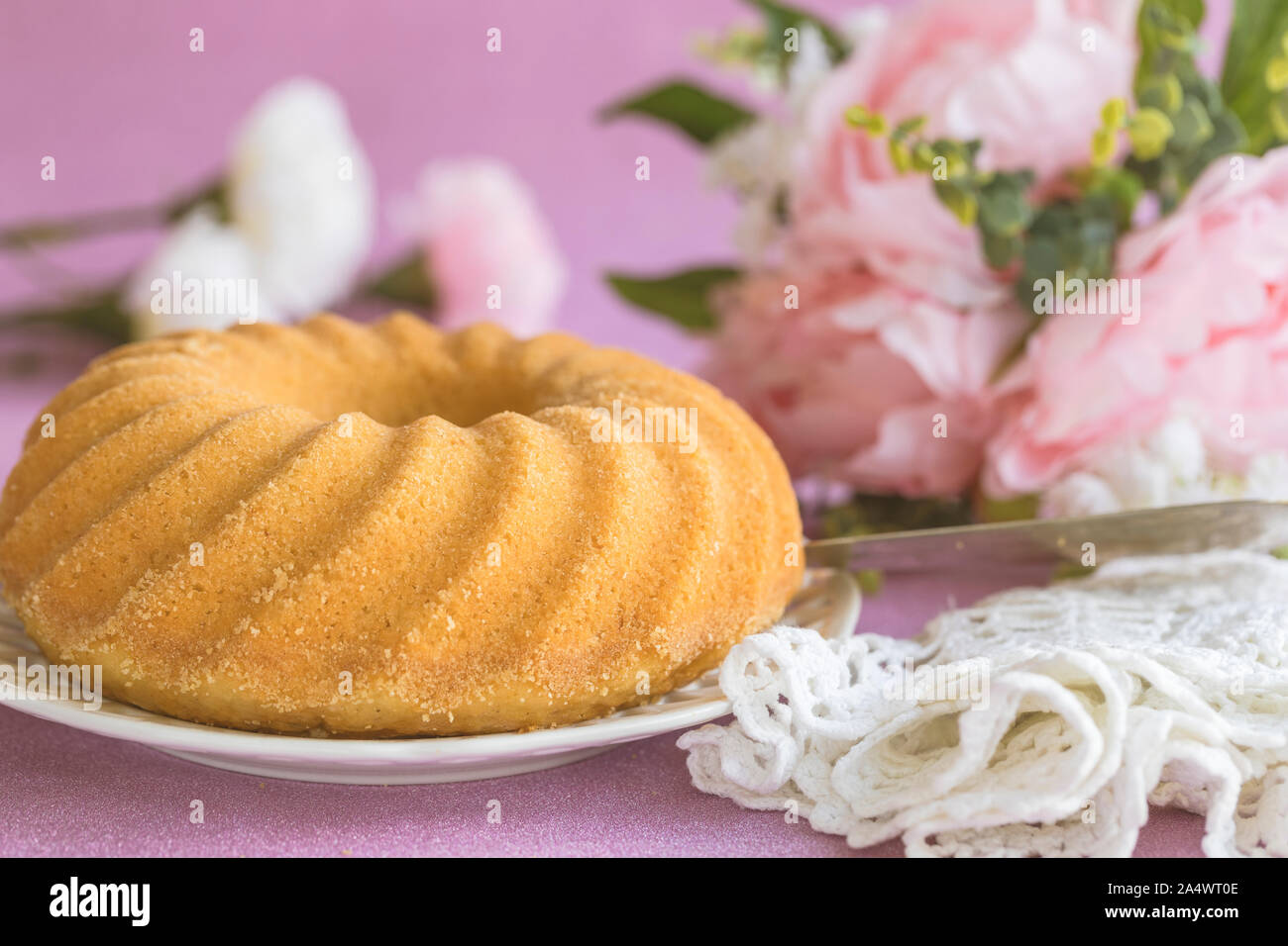 Gâteau éponge,Kugelhopf, Gâteau traditionnel suédois sockerkaka ou, sur un fond rose, entouré de fleurs et d'un romantique chiffon en bonneterie. Banque D'Images