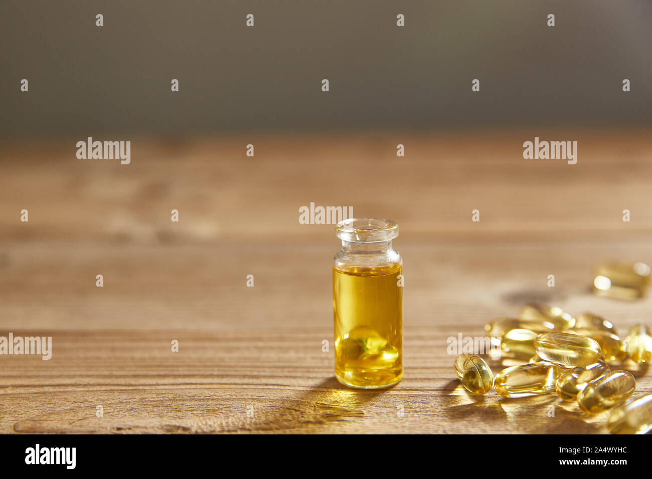 L'huile dans une bouteille en verre et huile capsules se situent sur une surface en bois. La biotechnologie pour l'extraction du pétrole et de l'emballage. place pour le texte. Banque D'Images