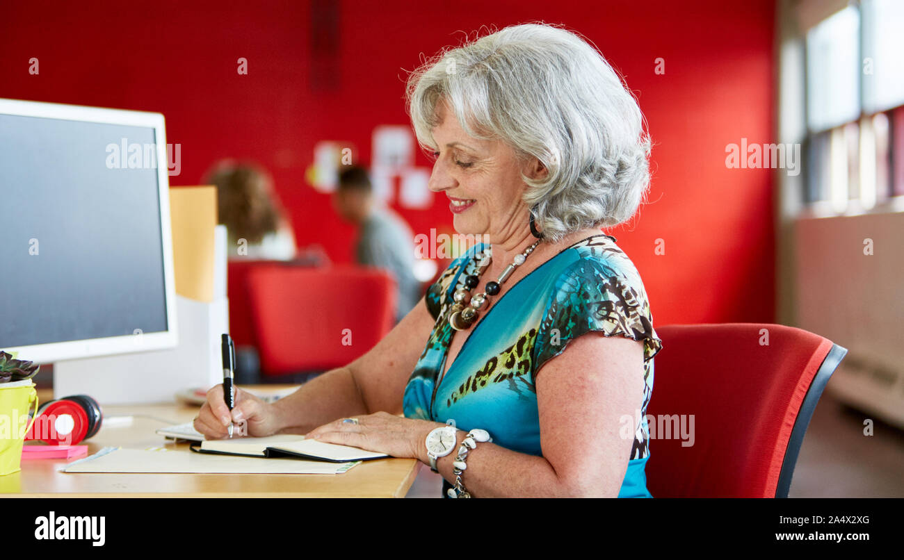 Confident female designer travaillant à son bureau en rouge de créatif Banque D'Images