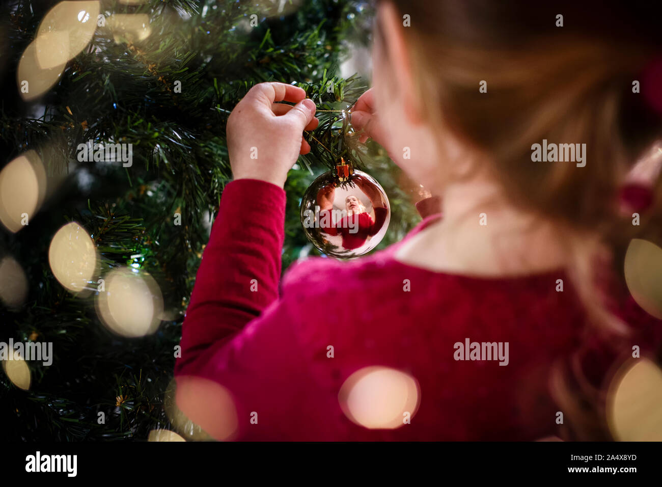 Image Fêtes d'girl decorating Christmas Tree dans réflexion bauble Banque D'Images