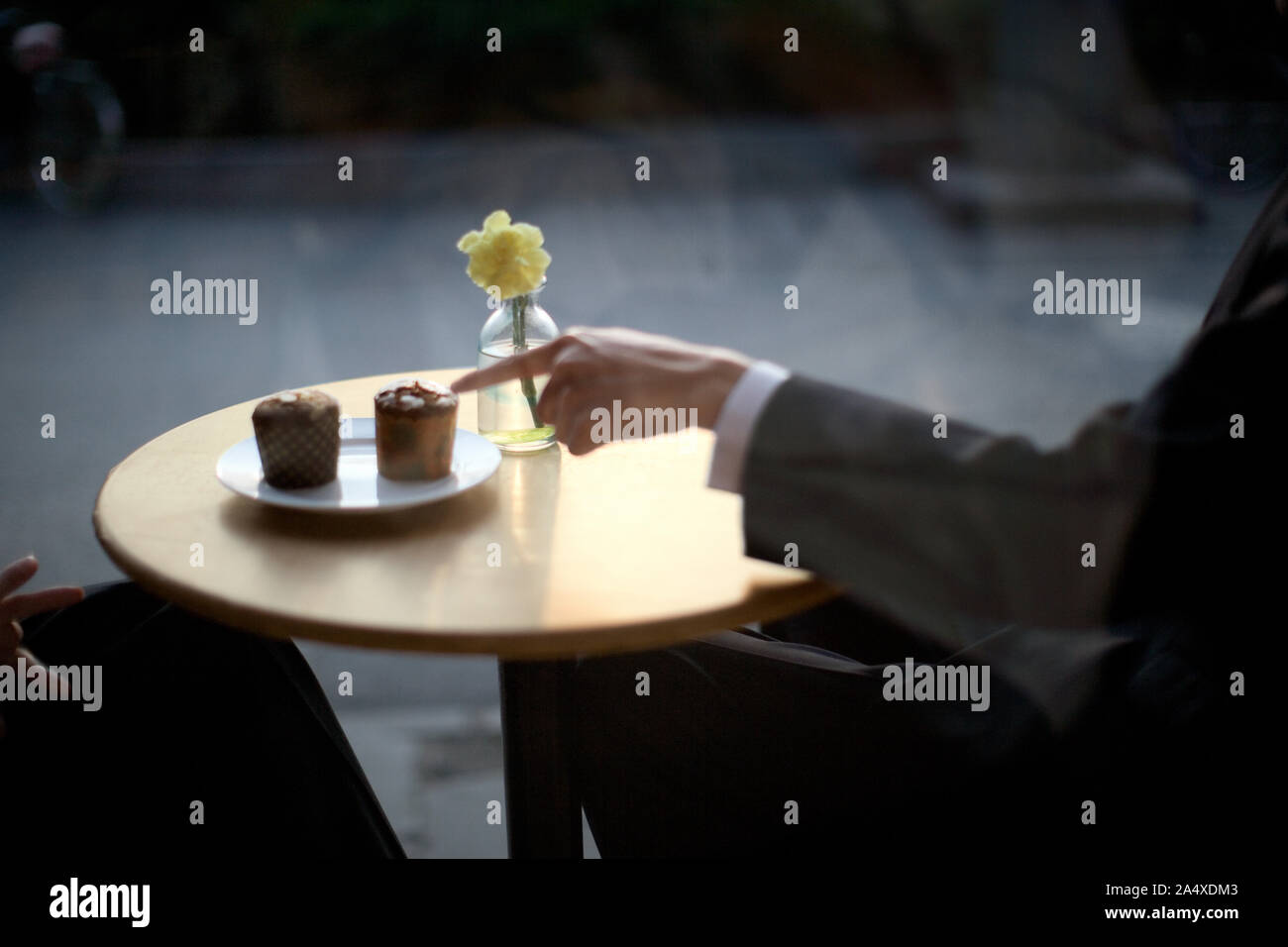 Muffins sur une table qui est pointé par un homme d'affaires. Banque D'Images