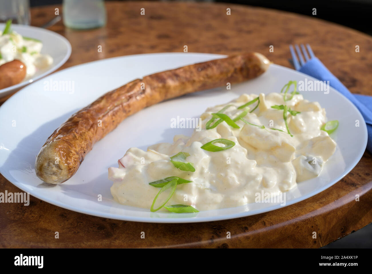 Saucisse bratwurst ou rôti sur le grill avec la salade de pommes de terre sur une plaque dans un restaurant de la rue étroite, de mise au point sélectionnée, la profondeur de champ Banque D'Images