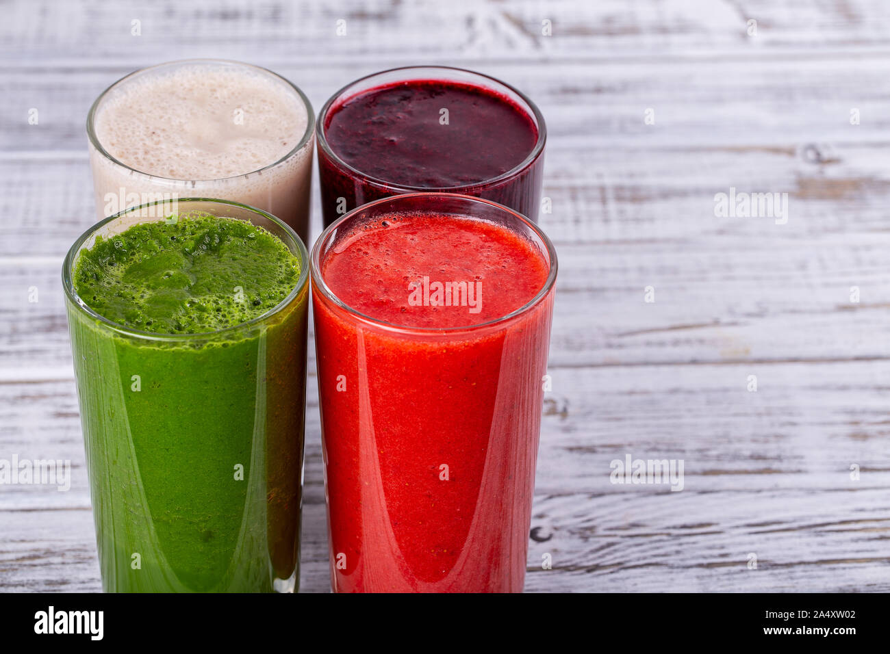 Avocat frais, fraise, bleuet et banana smoothie sur table en bois blanc. Cocktails sains avec des fruits frais. Close up quatre verres, copy space Banque D'Images