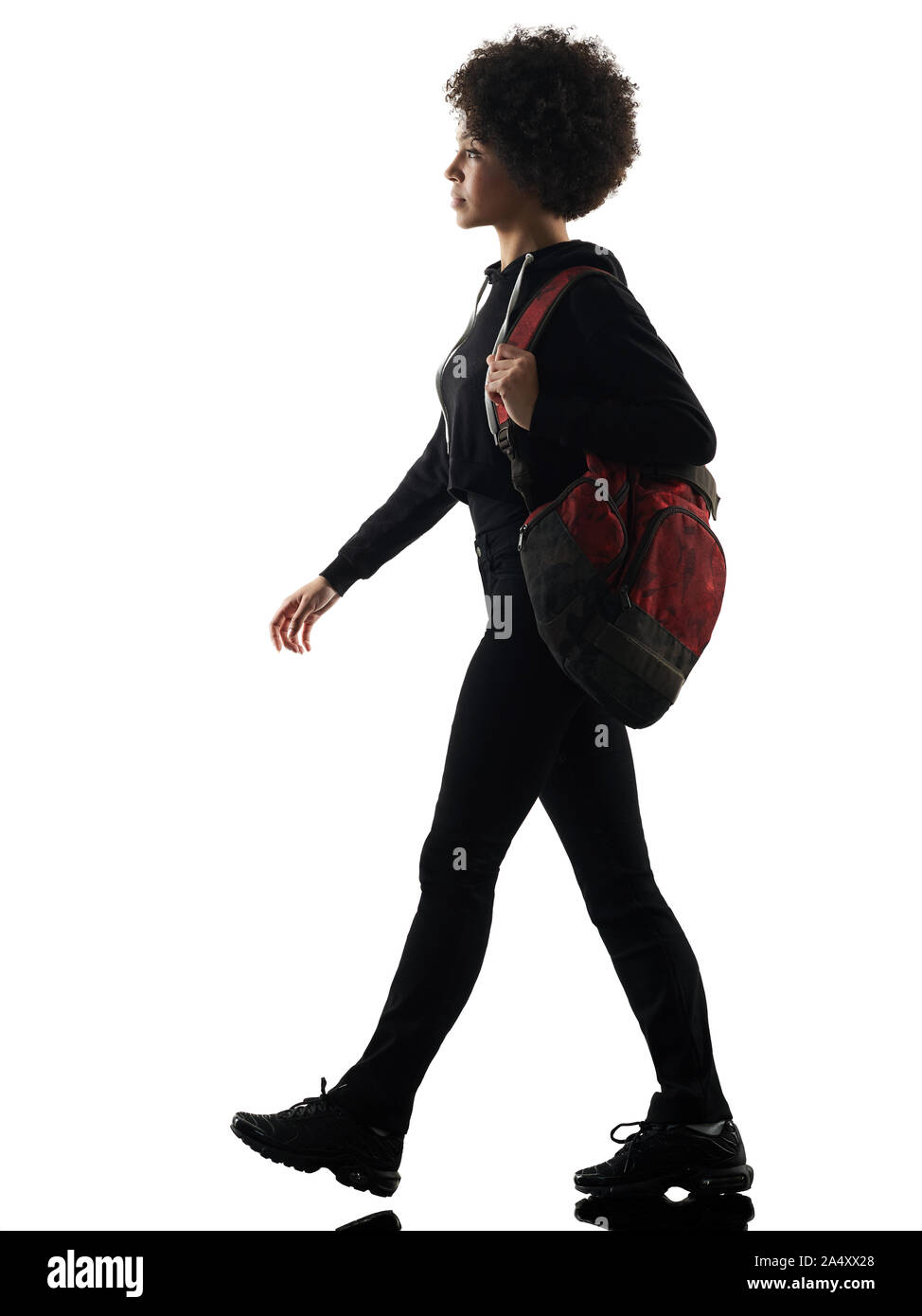 Un jeune adolescent africains mixed race girl woman walking in studio silhouette ombre isolé sur fond blanc Banque D'Images