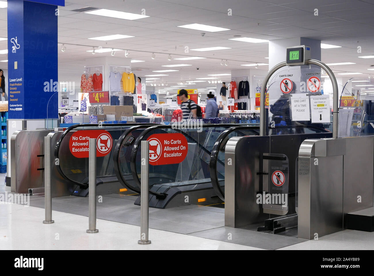Motion de personnes prenant des escaliers mécaniques dans l'intérieur moderne et urbaine à l'intérieur magasin Walmart Banque D'Images