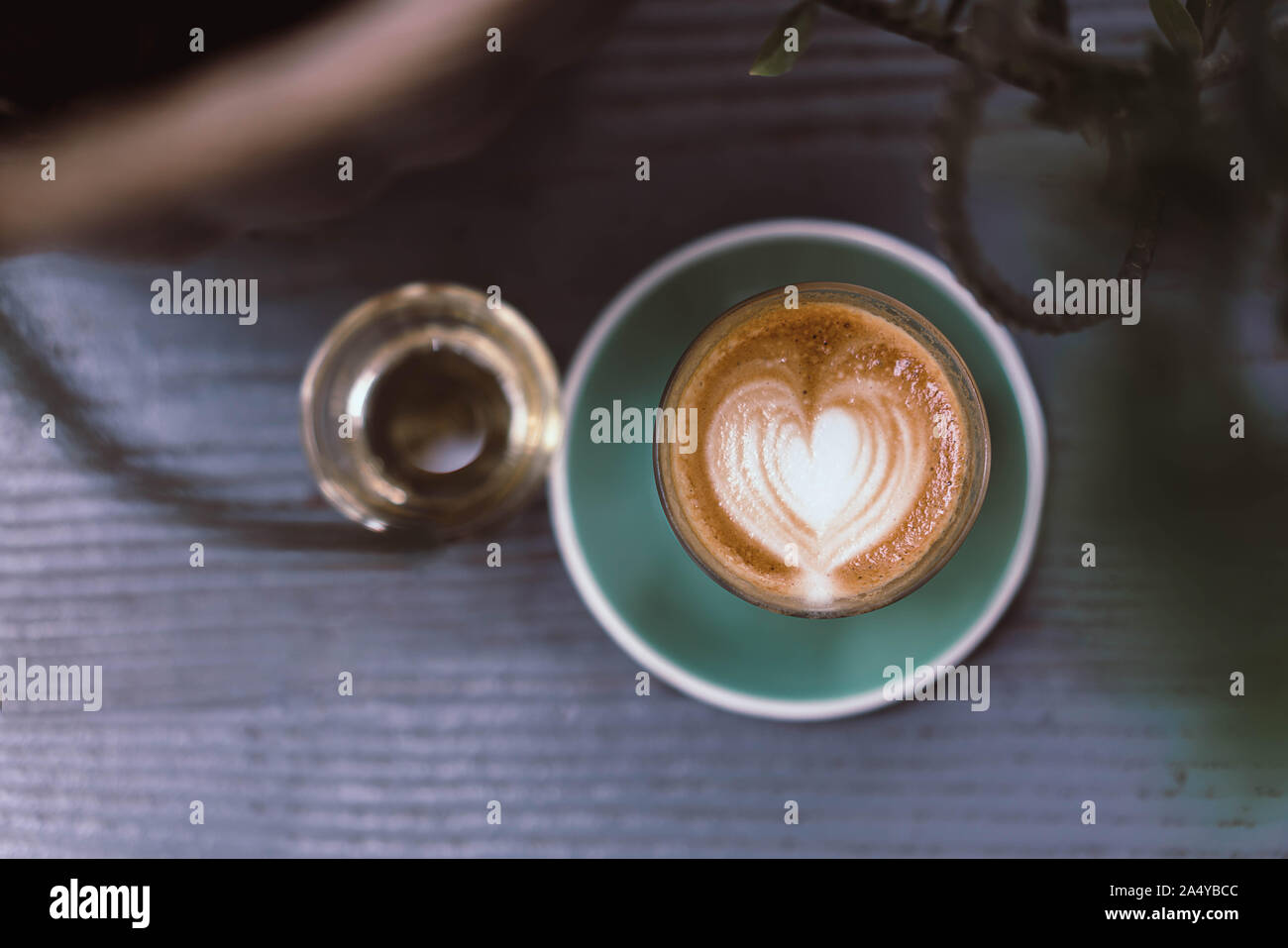 Tasse de café latte art avec soucoupe vert sur fond de bois Banque D'Images