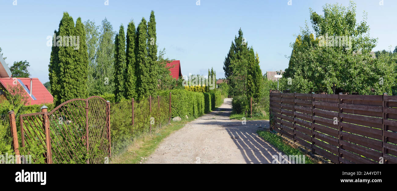 Vue en perspective d'une route et de haies vertes dans le standard européen pauvre village. Vue panoramique collage à partir de plusieurs photos journée ensoleillée d'été Banque D'Images
