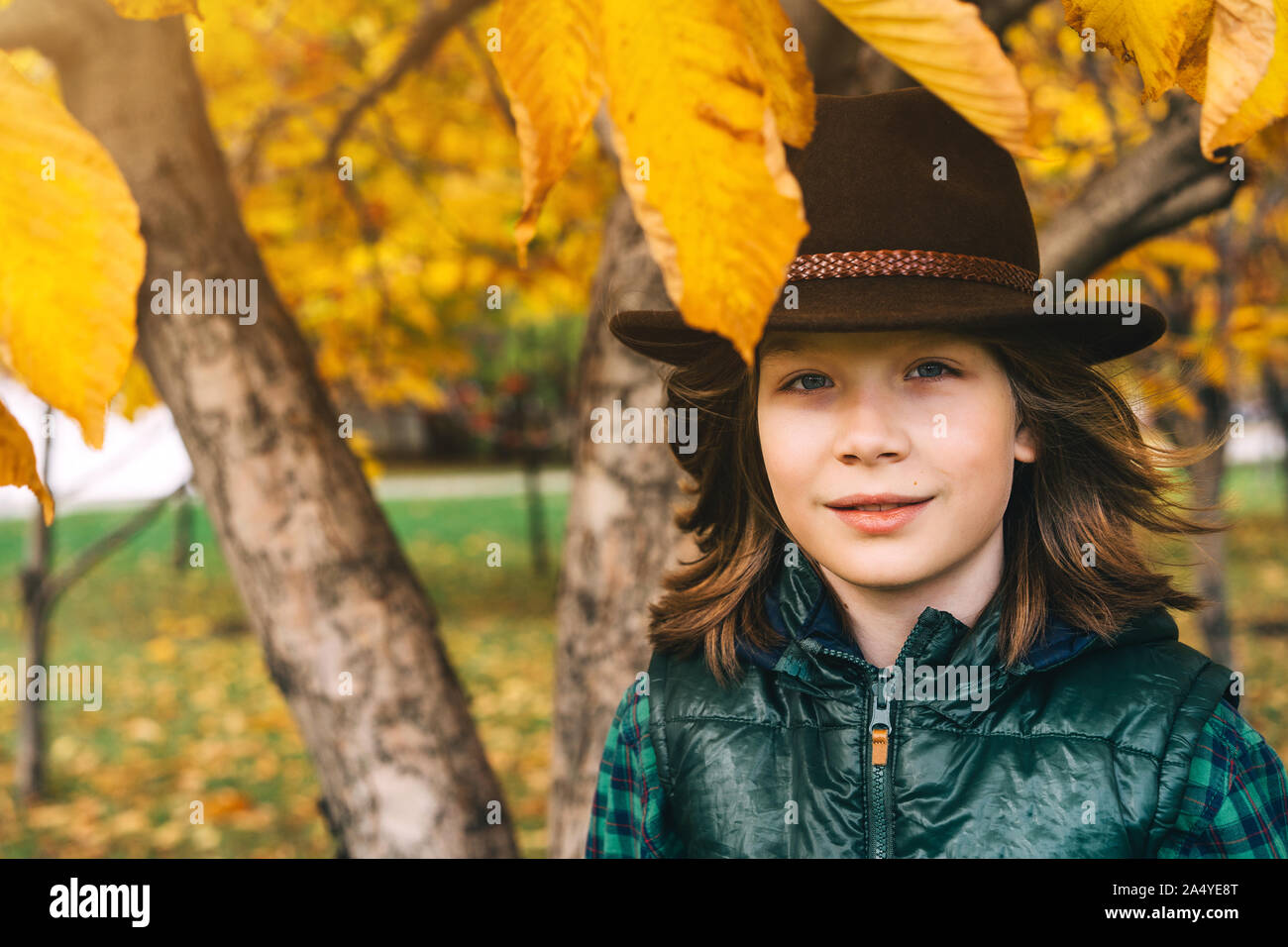 Un mignon petit garçon de 11 ans avec de longs cheveux bruns dans un chapeau de feutre de cow-boy Banque D'Images