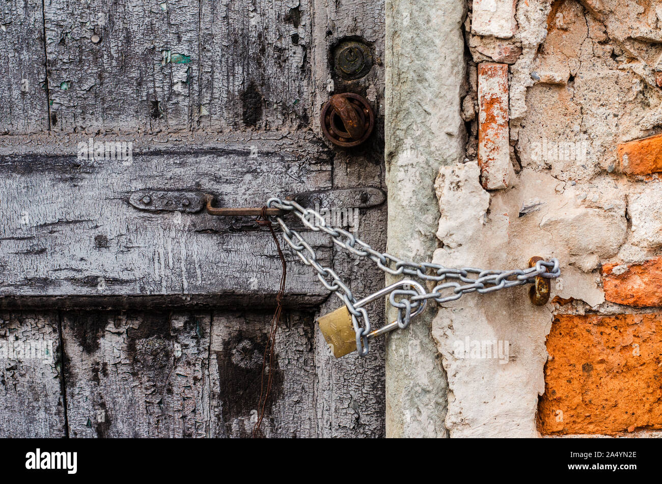 Une vieille porte en bois gris avec un cadenas verrouillé, enchaînés et lié à un vieux mur cassé en Toscane, Italie Banque D'Images