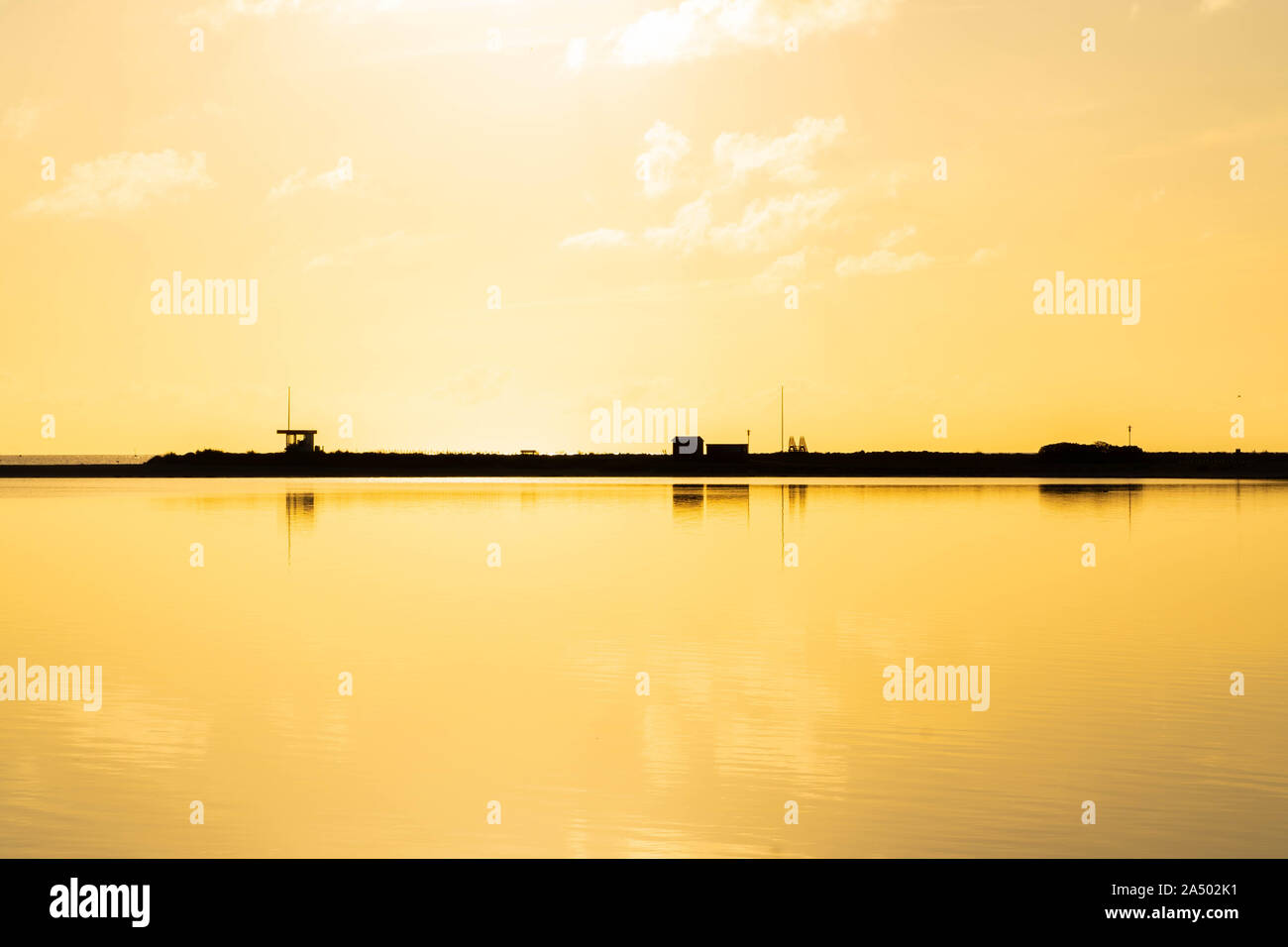 Heure d'or sur l'océan : la plage avec un baywatch tower couvert de lumière dorée, l'océan reflétant la lumière du soleil Banque D'Images