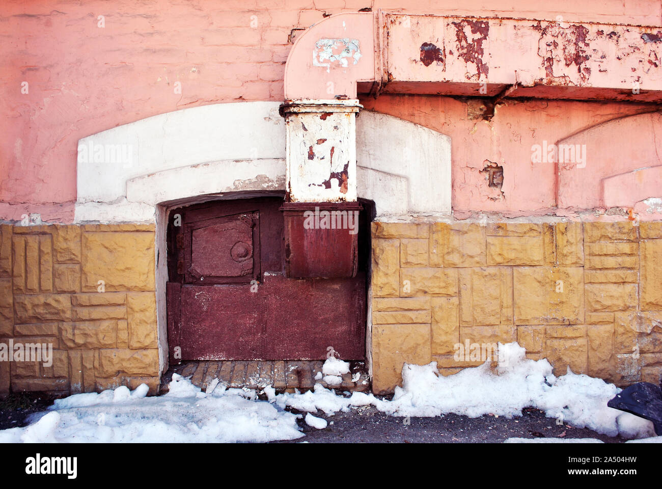 Mur de couleurs jaune, rose rouge à l'ancienne fenêtre placardées sur le terrain, tuyau de ventilation, la fonte de la neige sur l'asphalte, grunge ville horizontale détail Banque D'Images
