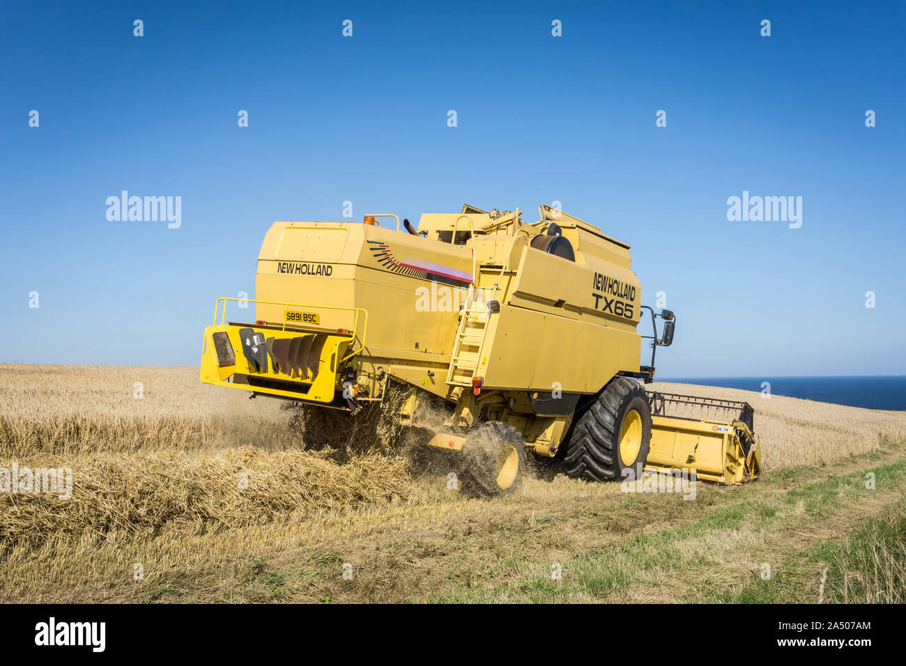 Une nouvelle moissonneuse-batteuse New Holland TX 65 en tenant à la récolte sur une journée ensoleillée. Banque D'Images