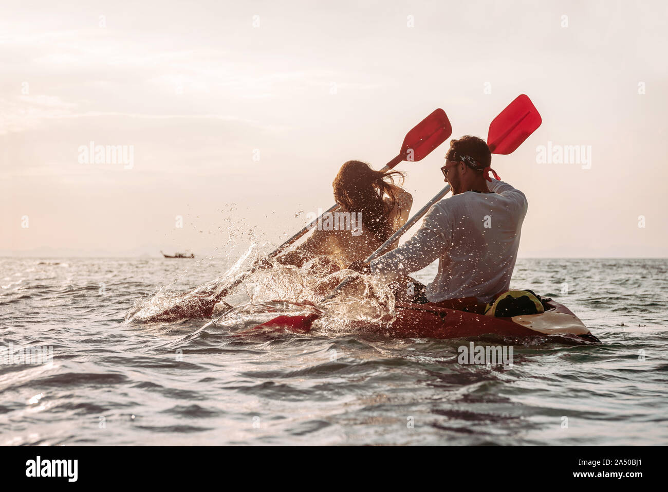 Couple heureux des balades en kayak de mer au coucher du soleil Banque D'Images