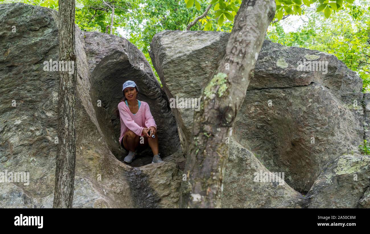 Asian Woman in hat chandail rose et accroupis dans rock en gros rocher Banque D'Images