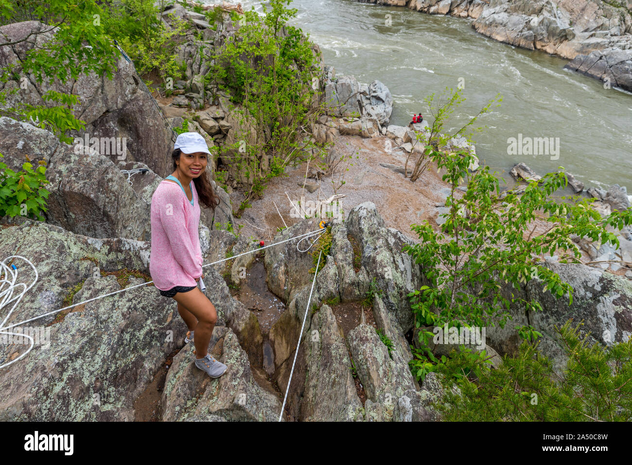 Woman in pink sweater standing par bord de la falaise avec des cordes d'escalade et la rivière dans l'arrière-plan Banque D'Images