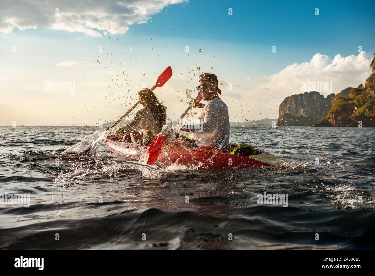 Couple heureux s'amuse et promenades sur la baie au coucher du soleil des kayaks de mer Banque D'Images