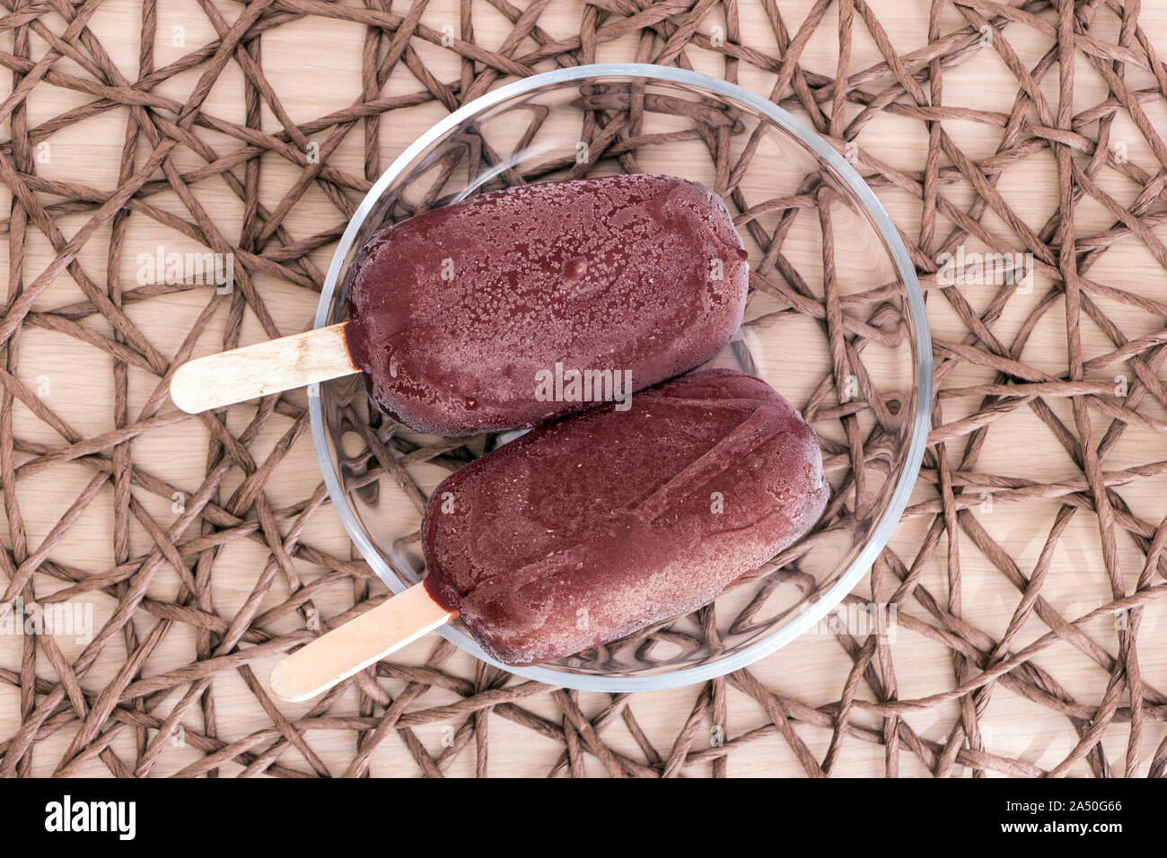 Vue supérieure de la matière première à des bâtonnets sucettes enrobées de chocolat glaze réside dans le bol transparent verre nappe en osier. Maison vegan délicieux Banque D'Images