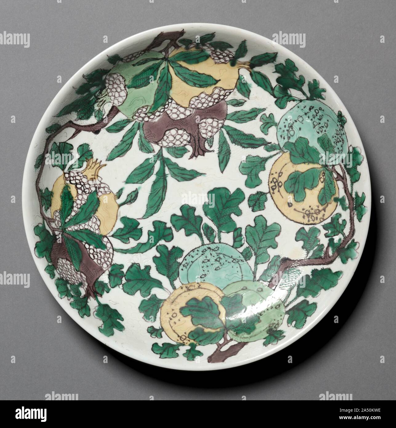 Plat avec des dragons, des grenades, et les pêches, 1662-1722. Différentes techniques sont appliquées à la décoration de susancai ou "plain" ware à trois couleurs. L'hidden dragons sont incisés, sur laquelle sont peints décoration de pulvérisations de fruits et de fleurs décrites avec pigment noir et couleur avec jaune, vert, turquoise, brun violacé et émaux. Le sol est rempli d'argile non émaillés sur émail Ivoire. Banque D'Images